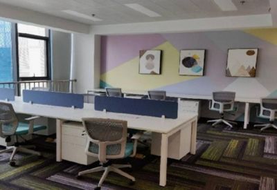 Modern open-plan office with white desks and colorful geometric wall art.