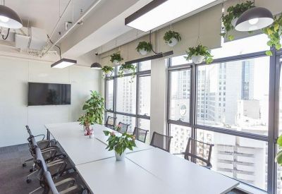 Bright conference room with a long white table, ergonomic chairs, and large windows overlooking the city.