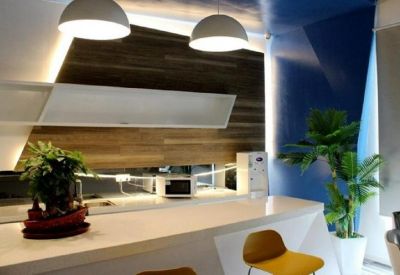 Communal break area featuring a modern white island, wood paneled walls, and vibrant green plants.