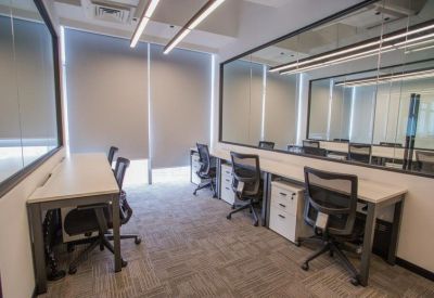 Private office suite with multiple workstations, ergonomic chairs, and glass partitions.