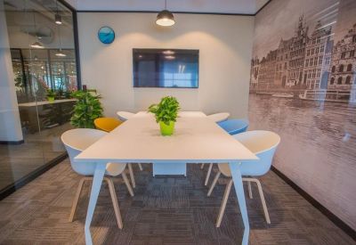 Bright meeting room with a white table, colorful chairs, and a city-themed wall mural.