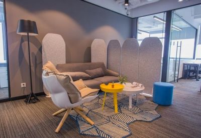 Cozy breakout area with a grey sofa, yellow coffee table, and sound-dampening partitions.