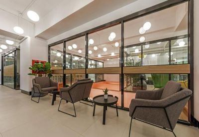 Lounge area with grey armchairs facing a glass-walled indoor sports court.