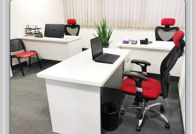 Spacious three-person office suite with white desks and ergonomic red chairs.