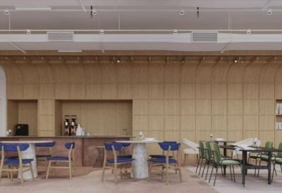 Communal breakout space with blue and green chairs and a marble-top table against a wood-slat feature wall.