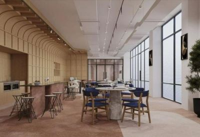 Spacious coworking area with blue velvet chairs, marble tables, and large industrial-style windows.