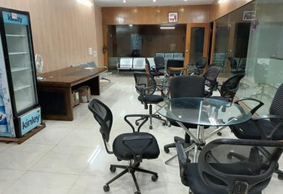 Communal break area with glass tables, black mesh chairs, and a refreshment fridge.