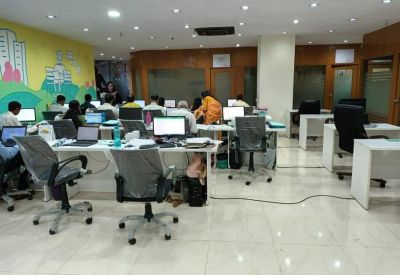 Spacious open-plan office with multiple workstations, grey chairs, and a colourful mural.