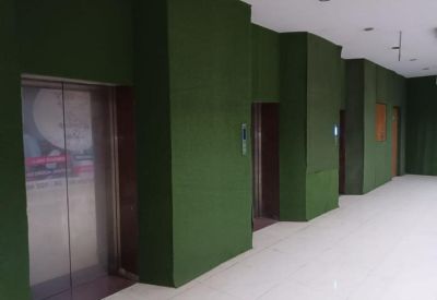 Bright hallway featuring green textured walls and several elevator doors.