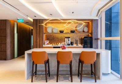 Breakout area featuring a stone island, orange bar stools, and a designer gold light fixture.