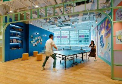 Spacious communal recreation area featuring people playing table tennis under a green archway.