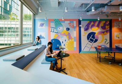 Bright breakout space with vibrant wall murals, a table tennis table, and a tiered seating area.