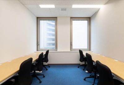 Bright private office featuring two desks with black chairs and a blue carpeted floor.