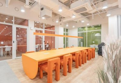 Collaborative workspace featuring a long orange communal table with unique arch-style stools.