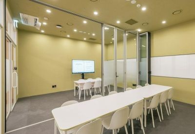 Modern meeting room with a long white table, matching chairs, and glass partition walls.