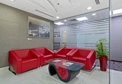 Comfortable waiting area with bright red armchairs and a designer glass coffee table.