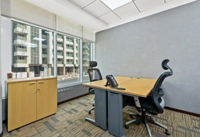 Private office with a light wood desk, ergonomic chairs, and large windows.