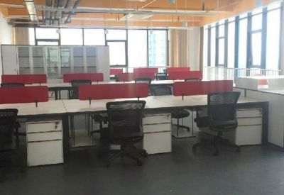 Modern open-plan office space featuring white desks with red privacy dividers and black ergonomic chairs.