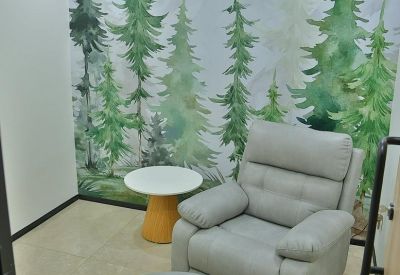 Quiet relaxation room featuring a grey recliner, footrest, and forest mural.