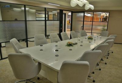 Spacious boardroom with a large white table and ergonomic grey chairs.