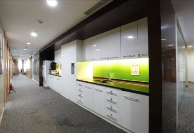 Sleek kitchen and break area with white cabinetry and a bright green backsplash.