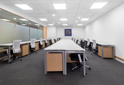 Large open-plan office with white desks and rows of ergonomic chairs.