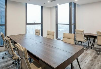 L-shaped office layout with collaborative wooden desks and ergonomic beige chairs.