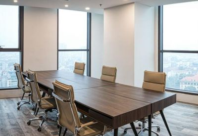 Bright conference room featuring a large wooden table and city views through floor-to-ceiling windows.
