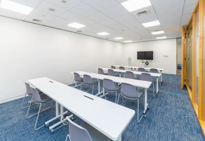 Training room with white flip-top tables and blue carpet.