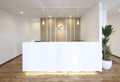 Minimalist white reception desk featuring warm under-lighting and a potted plant.
