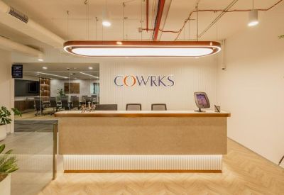 Bright reception area with a light wood desk under a large oval pendant light.