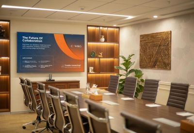 Executive boardroom with a long dark wood table, leather chairs, and a large display screen.
