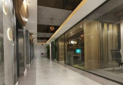 Modern office corridor featuring glass-walled suites and neutral tiling.