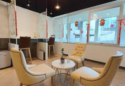 Bright breakout area with cream-colored tufted armchairs and a decorative flower pendant light.