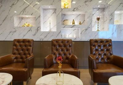 Upscale waiting area with brown leather tufted armchairs against a white marble feature wall.