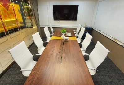 Modern conference room featuring a long wood-grain table and white executive chairs.