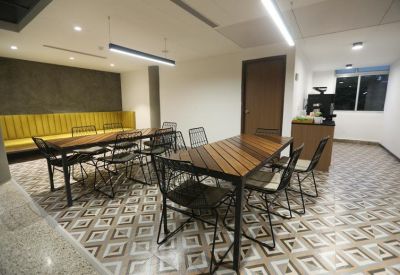 Modern dining area with patterned floor tiles, wooden tables, and a yellow banquet bench.