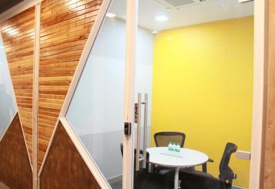 Private glass-walled meeting room with a yellow accent wall.