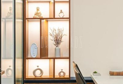 A floor-to-ceiling wooden display shelf with warm internal lighting showcasing small sculptures.
