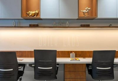 Shared workspace with long desk, ergonomic black chairs, and overhead storage cabinets.