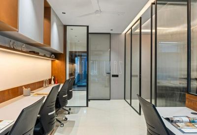 View through glass partitions into a bright, contemporary workspace with multiple desk rows.