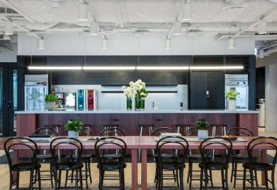 Spacious communal kitchen area with long wooden tables and black bistro chairs.