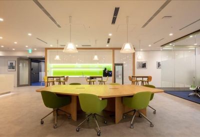 Spacious communal lounge with a large wooden table and vibrant green chairs.