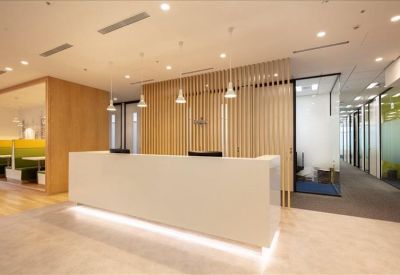 Sleek white reception desk backed by a decorative vertical wooden slat wall.