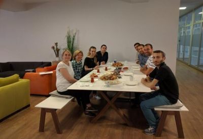 Staff sharing a meal at a long white dining table in a bright, modern breakout space.