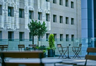Outdoor terrace with tables and chairs overlooking a city building facade.