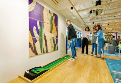 Communal breakout space featuring an indoor mini-golf putting green and colorful wall art.