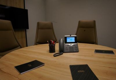 Round meeting table equipped with a conference phone and branded notebooks.