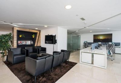 Stylish lounge area with black leather armchairs and a nearby open-plan workspace.