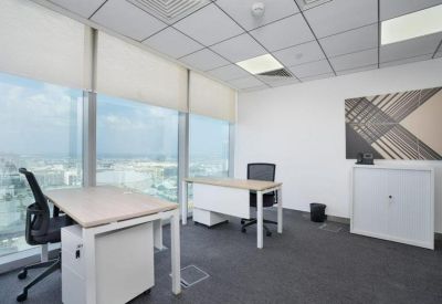 Bright corner office with two white desks and large windows overlooking the city.